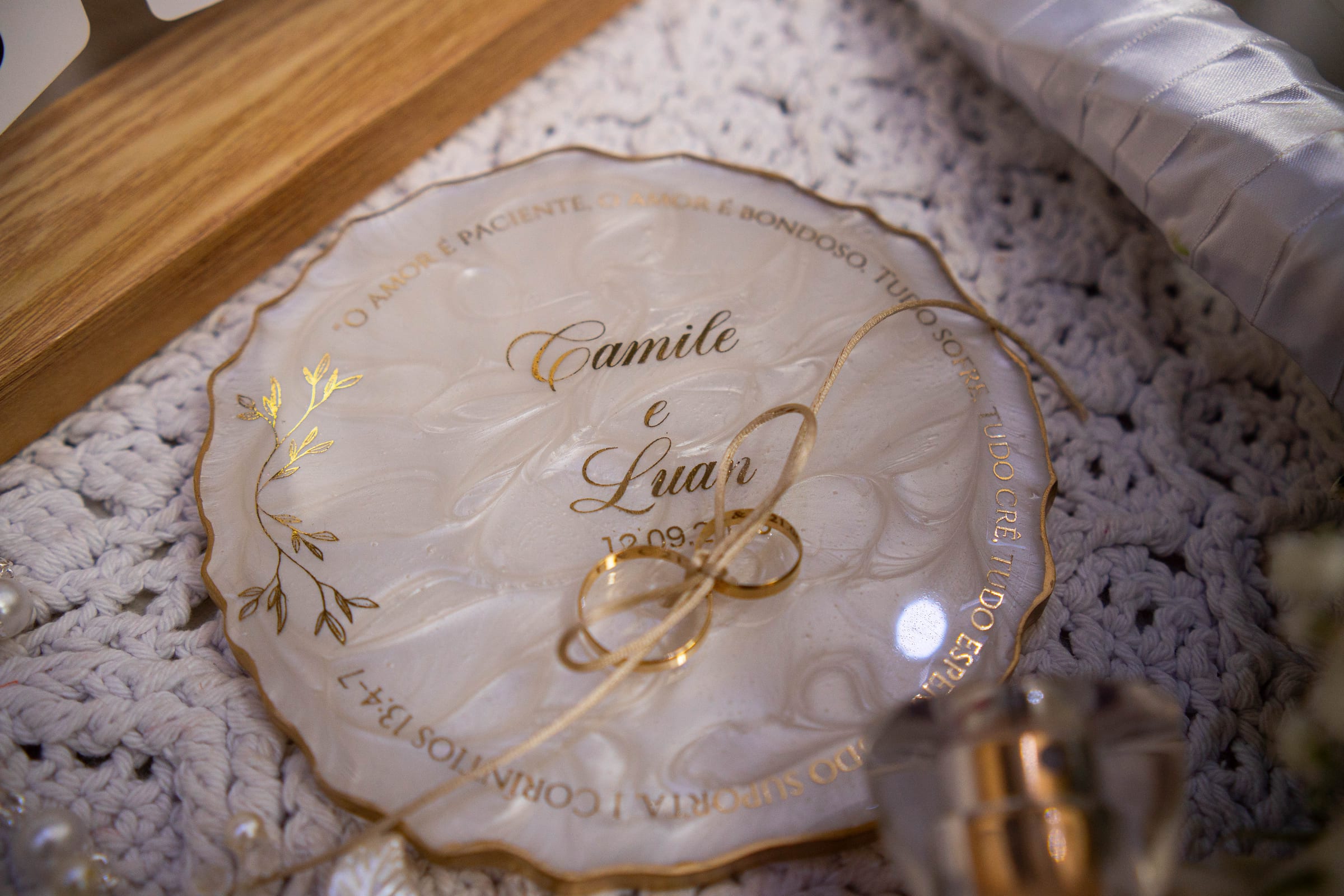 As alianças sobre a placa de acrílico com os nomes Camile e Luan
